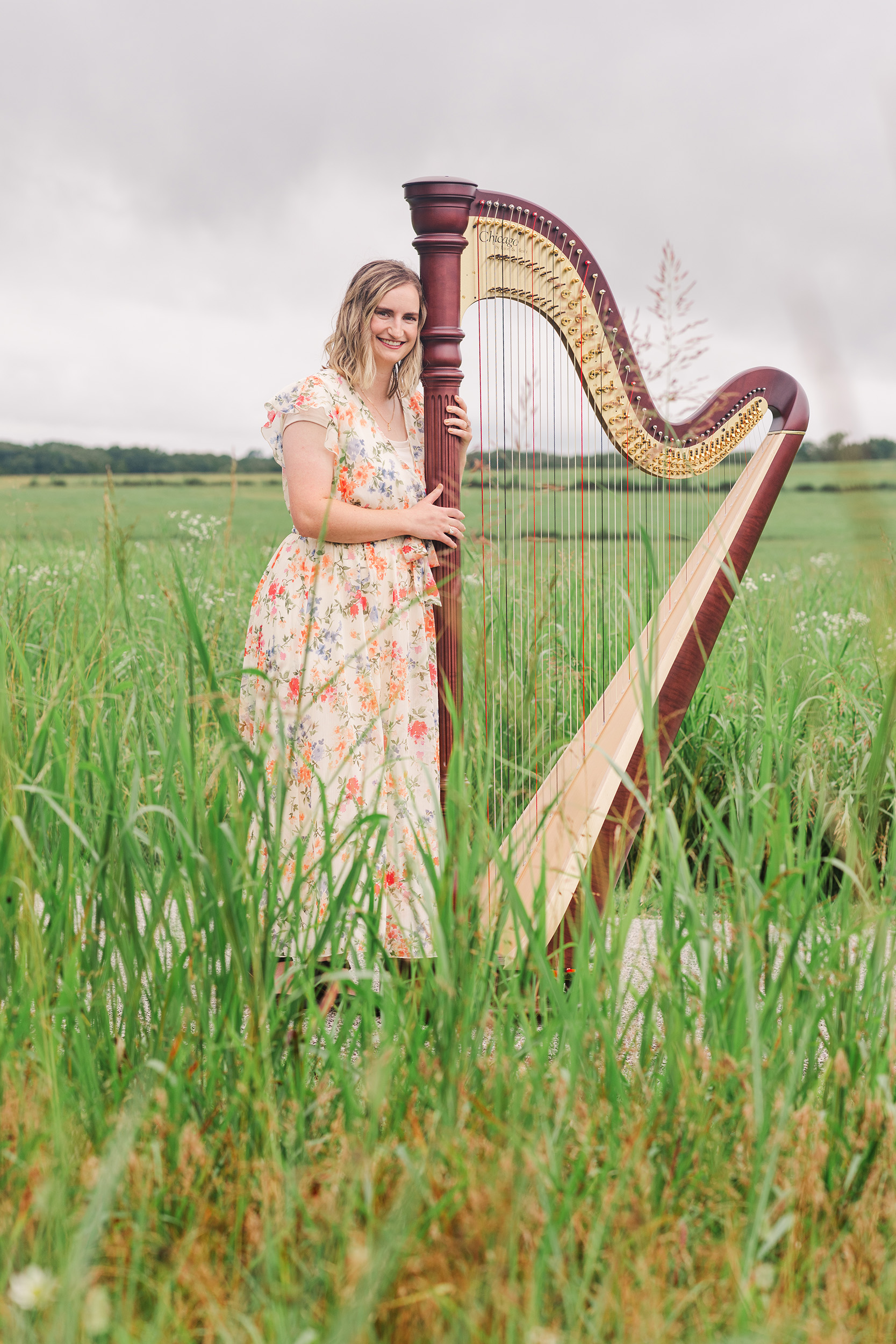Jenna Wilde standing with a harp